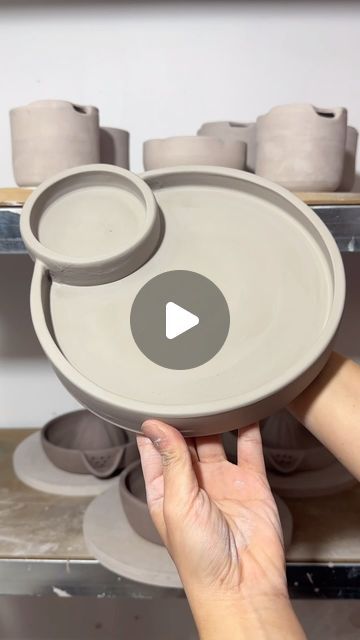 a person holding a bowl in front of some bowls on a shelf with other dishes