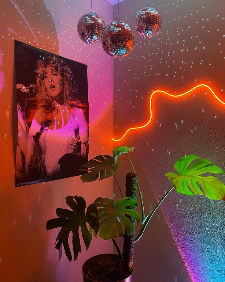 a room with disco ball lights and a painting on the wall next to a potted plant