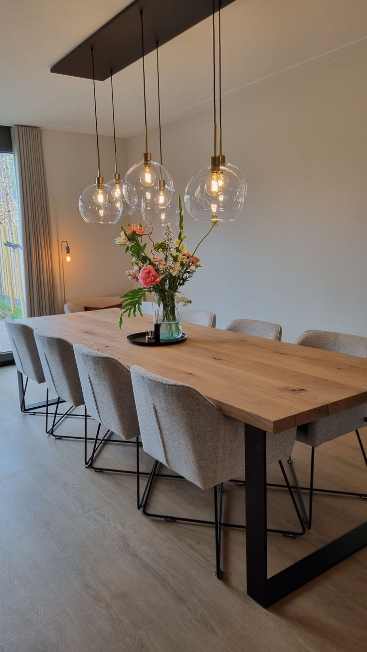 a dining room table with six chairs and a vase filled with flowers on top of it