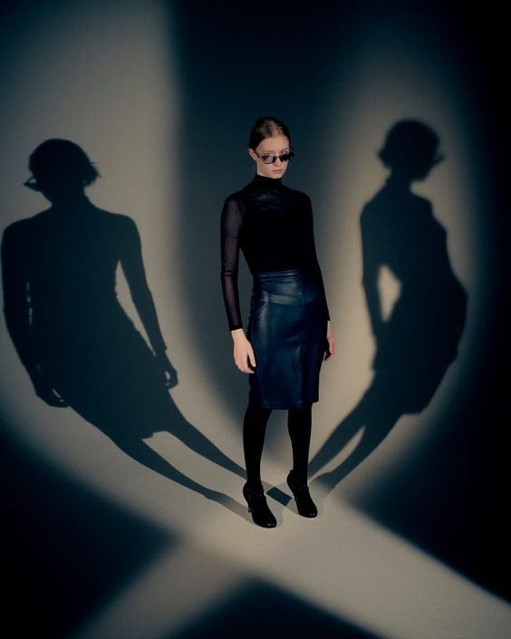 a woman standing in front of a shadow on the wall