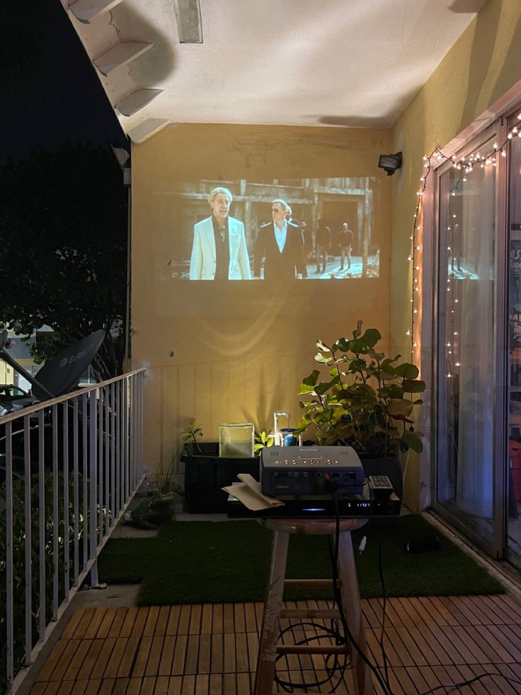 a screen on the outside of a house that is lit up with lights and plants