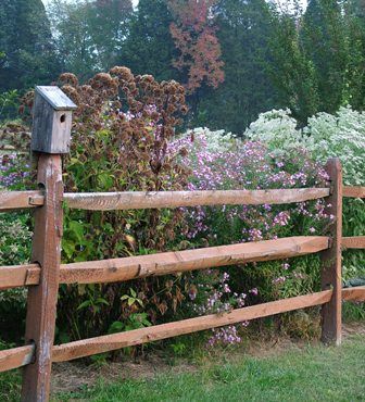 a wooden fence surrounded by flowers and trees