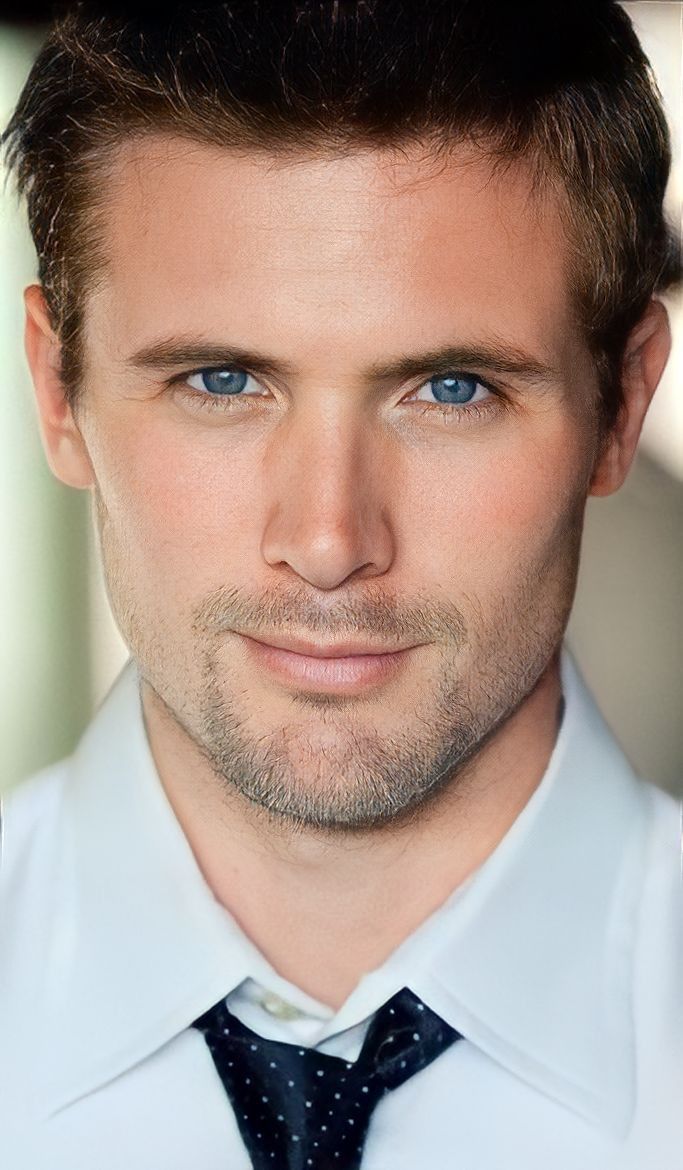 a close up of a person wearing a white shirt and black tie with blue eyes