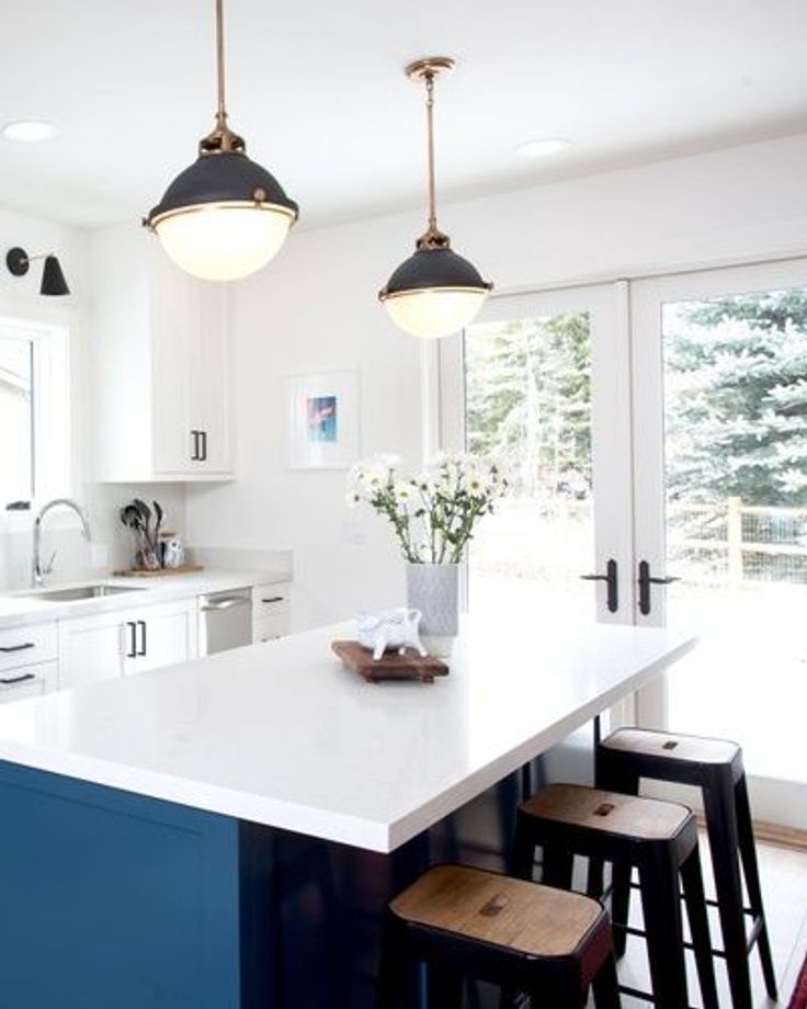 a kitchen island with stools in front of it and two lights hanging from the ceiling