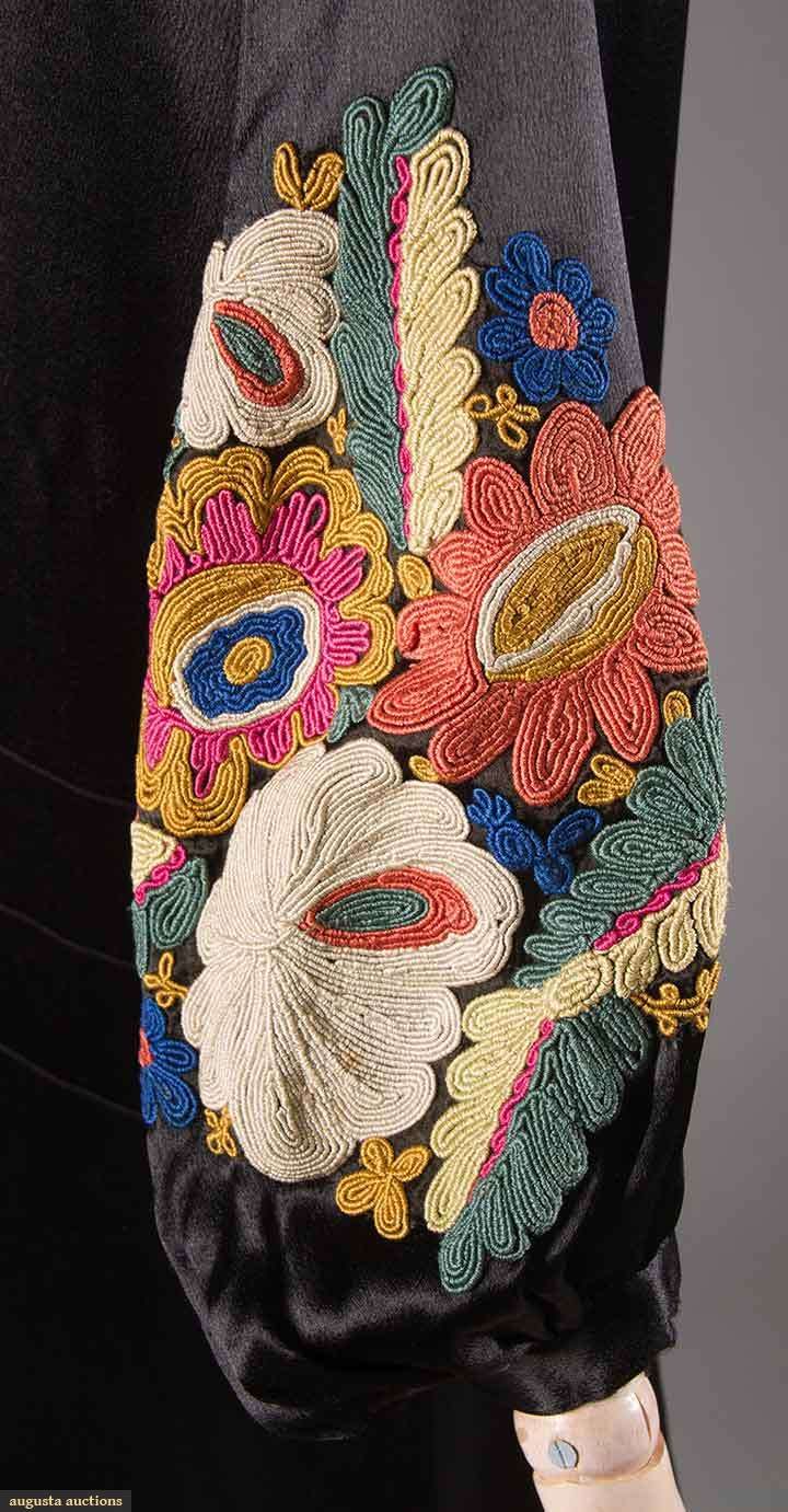 a woman's handbag with embroidered flowers and leaves on the front, attached to her purse