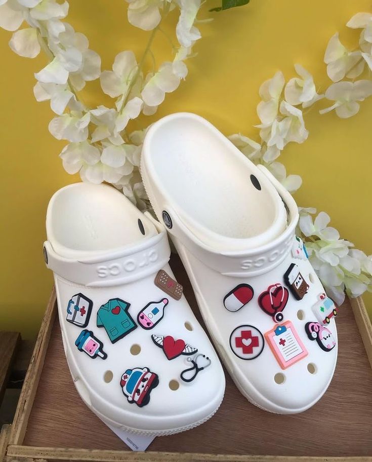 a pair of white clogs with medical icons on them