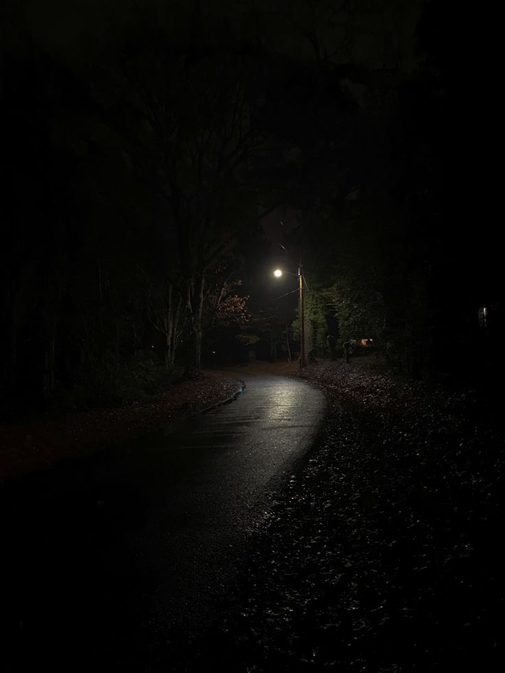 a dark road at night with the light on