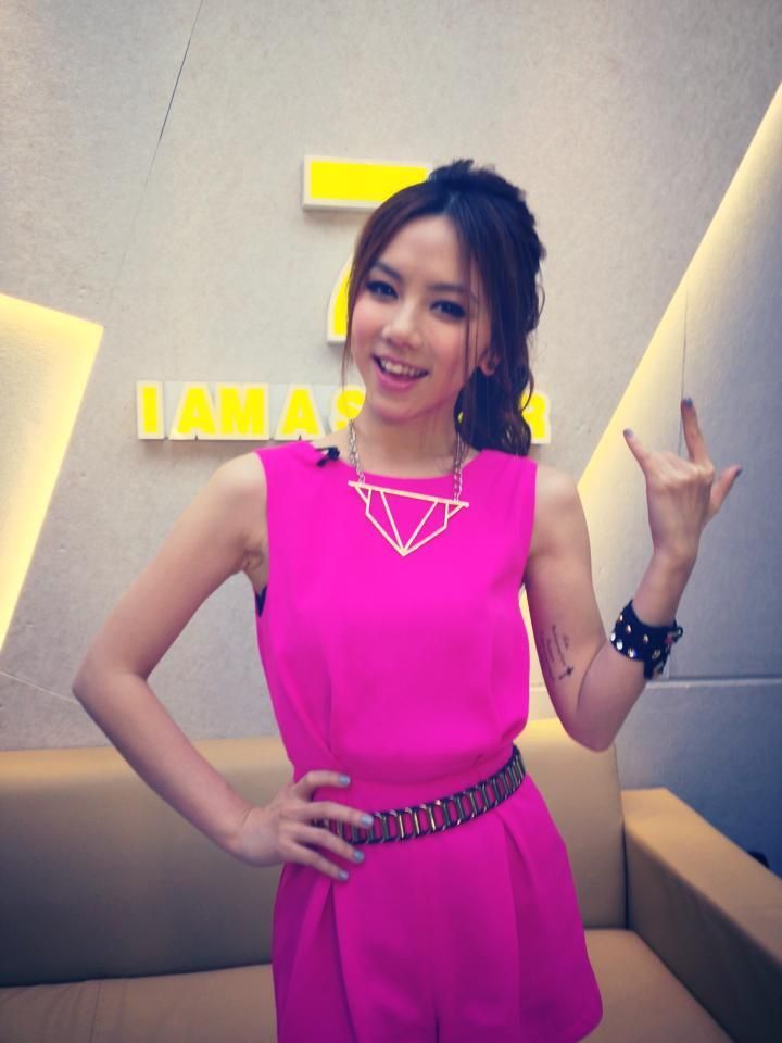 a woman in a bright pink dress posing for the camera with her hand up and smiling