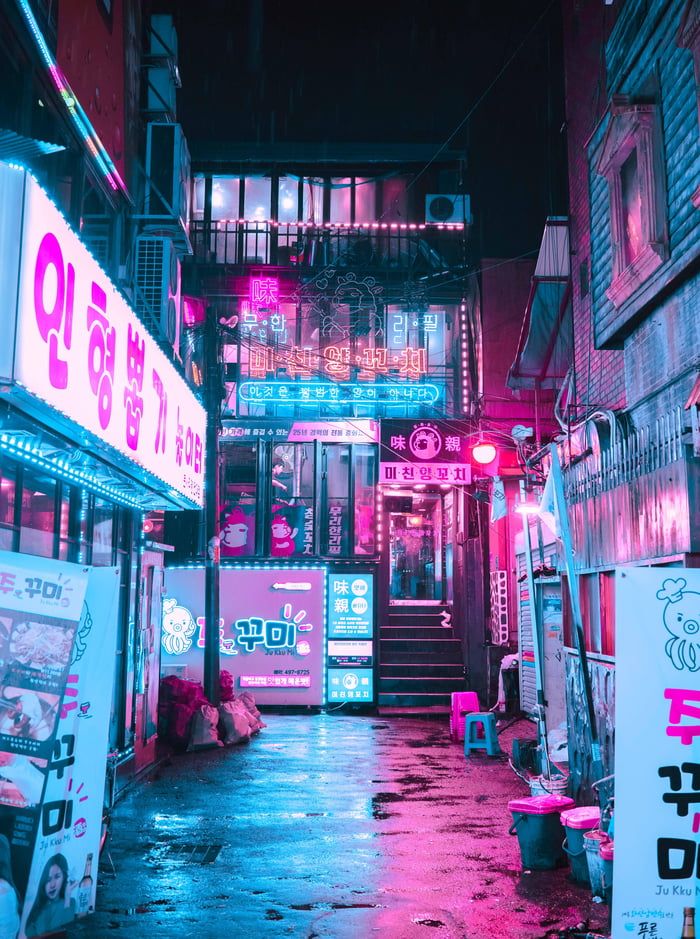 an alley way with neon lights and signs