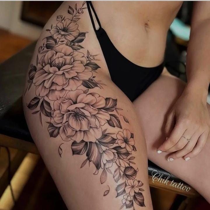 a woman is sitting on a chair with flowers tattooed on her leg and the bottom half of her thigh