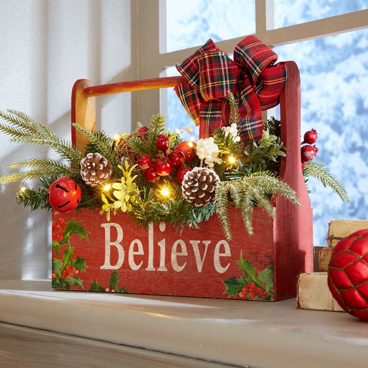 a wooden box filled with christmas decorations on top of a window sill