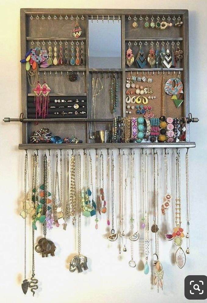 a wooden shelf filled with lots of necklaces and earring hooks hanging from it's sides