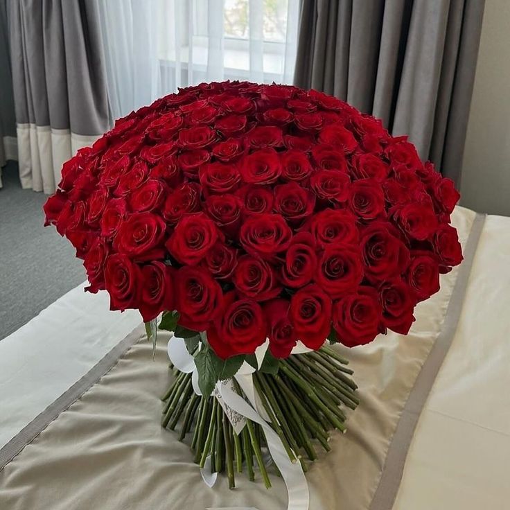 a large bouquet of red roses on a bed