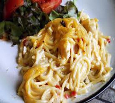 a white plate topped with pasta and veggies next to a salad on top of a table