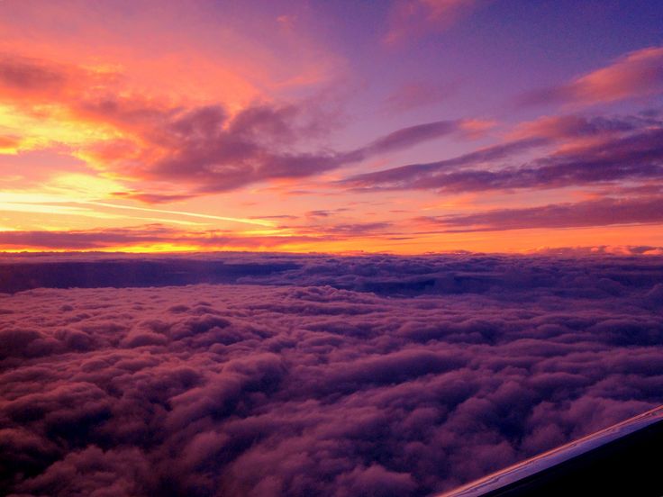 the view from an airplane looking down on some clouds and sunset in the sky above