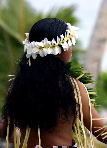 a woman with flowers in her hair walking down the street wearing a hula skirt