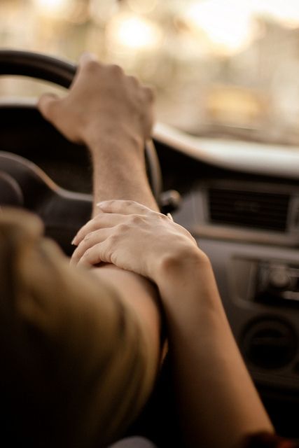 a black and white photo of someones hand on the steering wheel