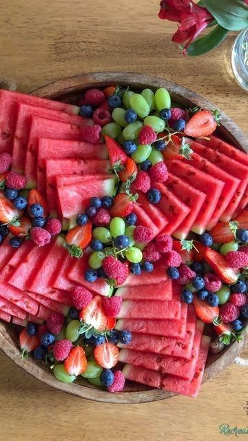 watermelon slices, grapes and strawberries arranged in a bowl on a table