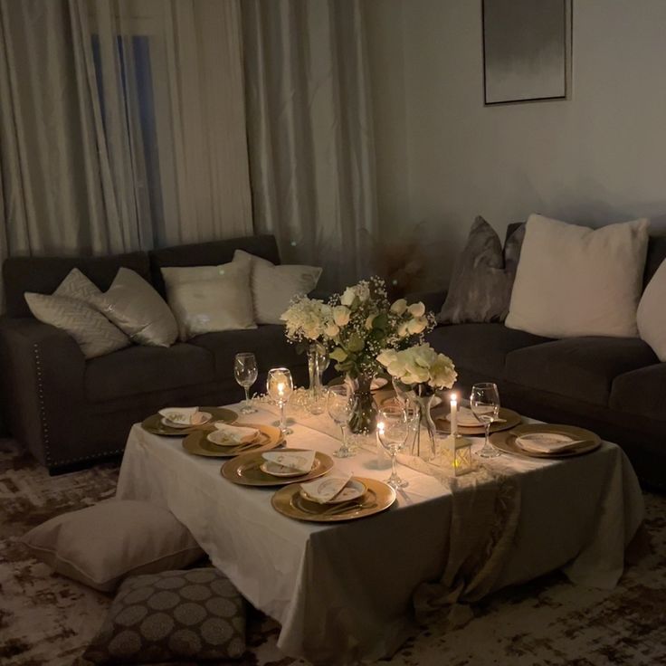 a living room filled with furniture and table covered in white cloths next to a couch