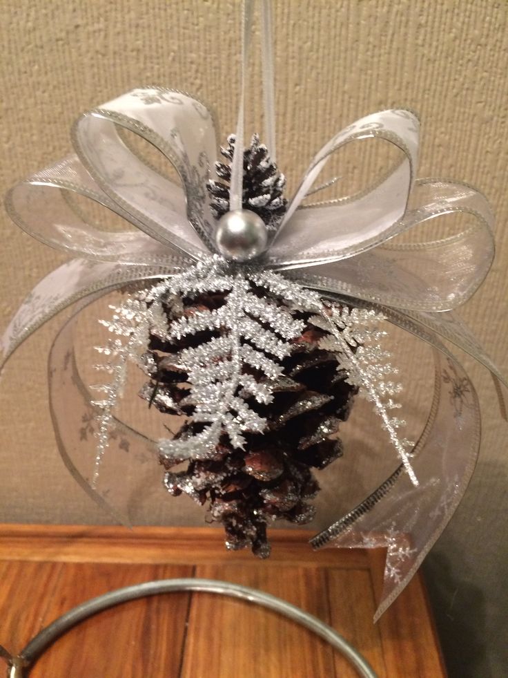 a pine cone hanging from a wire with snow flakes on it and a ribbon