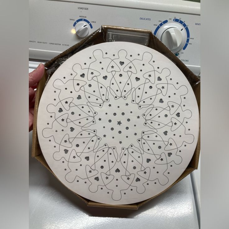 a white plate with black designs on it sitting on top of a dryer door