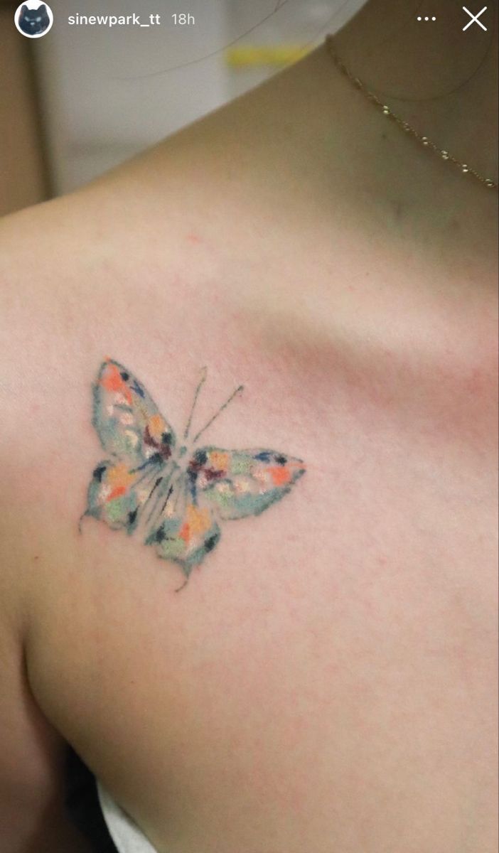 a small butterfly tattoo on the back of a woman's left shoulder and chest