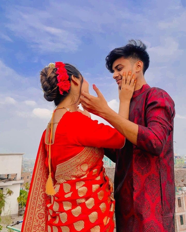 a man and woman standing next to each other on top of a roof with buildings in the background