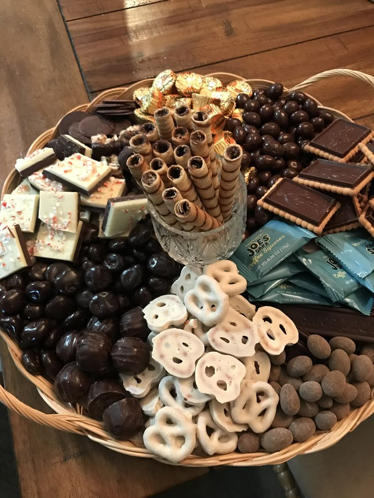 a basket filled with assorted chocolates and pretzels on top of a wooden table