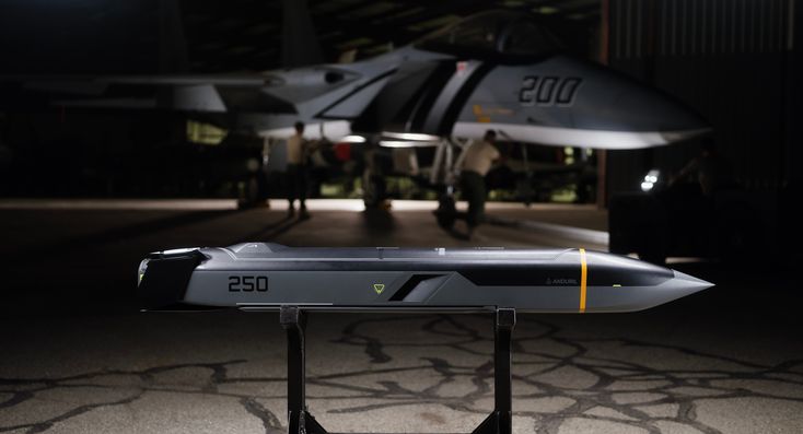 a fighter jet sitting on top of a metal stand in front of a hangar at night