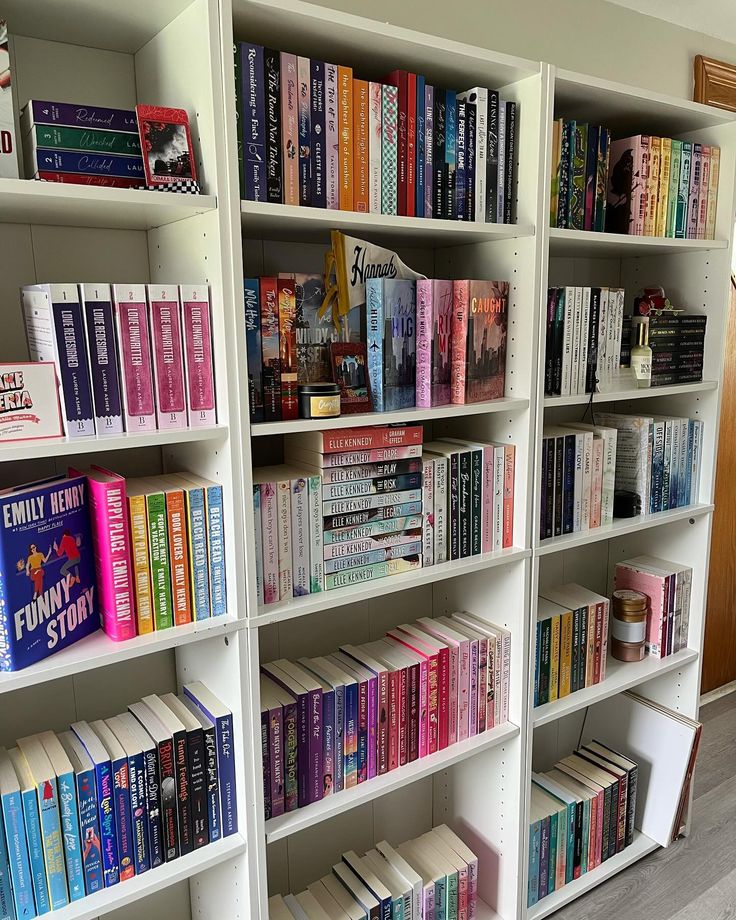 a book shelf filled with lots of books on top of white shelving units in a room