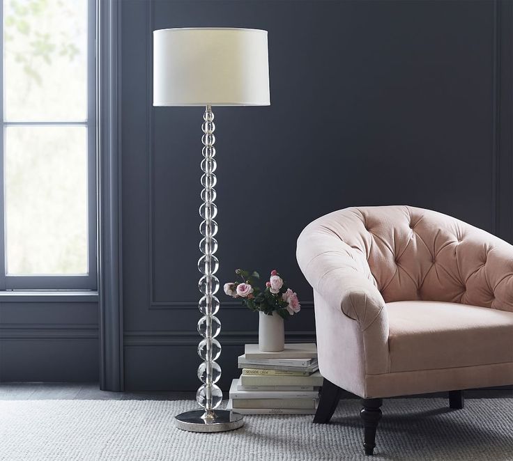 a living room with a chair, lamp and books on the floor in front of a window