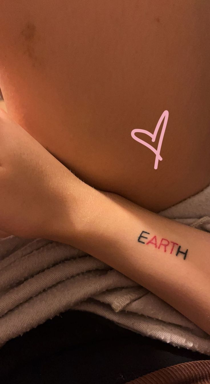 a woman's arm with the word earth tattooed on it