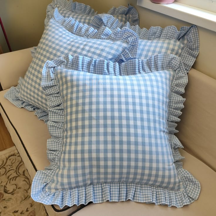 three blue and white gingham pillows sitting on a couch next to a window