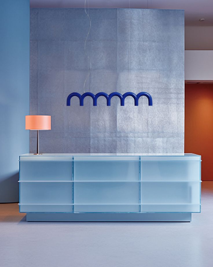 a blue reception counter in front of a wall with the m m logo on it