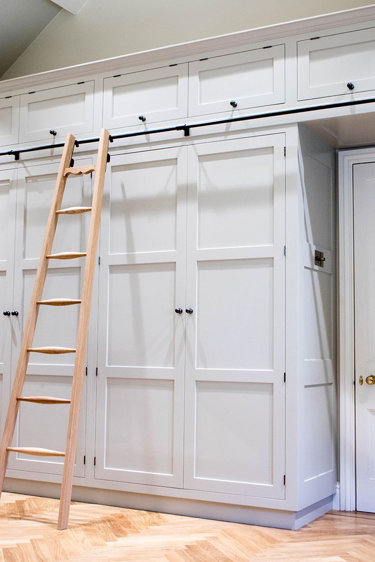 a ladder leaning up against the wall in a room with white cupboards and wooden floors