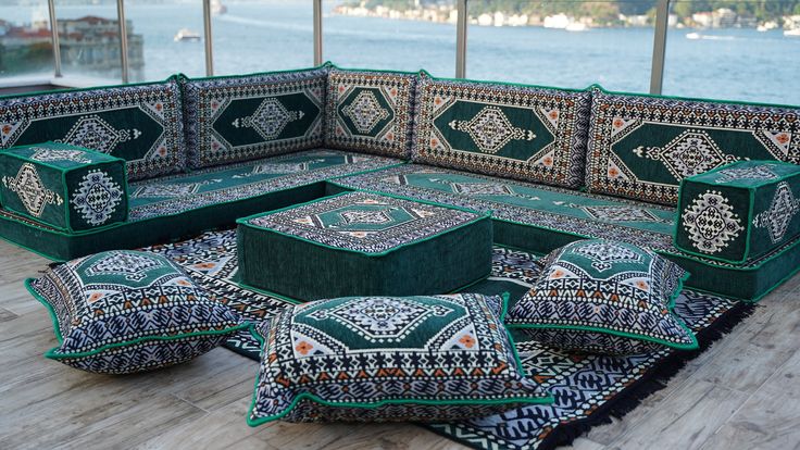 a green couch sitting on top of a wooden floor next to pillows and rugs