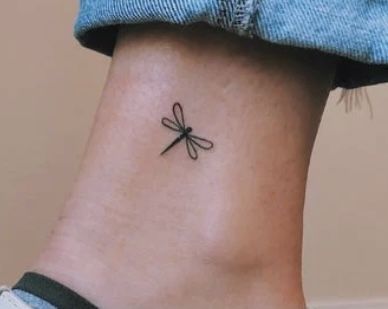 a small tattoo on the ankle of a woman with a dragonfly on her left side