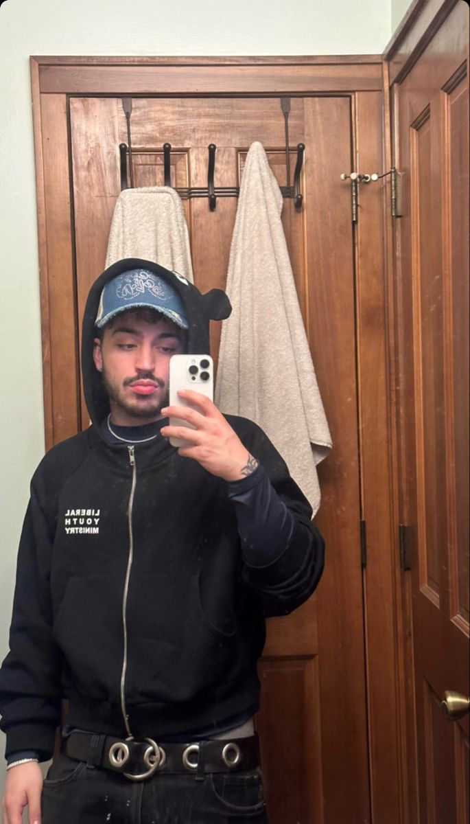 a man taking a selfie with his cell phone in front of a wooden closet