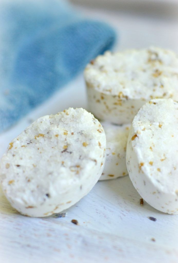 three white cookies with sprinkles on them sitting on a blue and white cloth