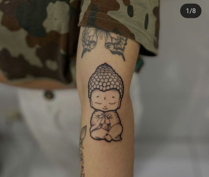 a person with a tattoo on their arm that has a buddha image on the side