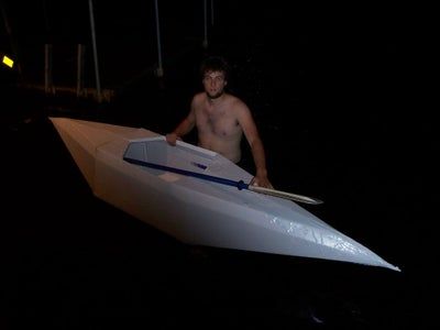 a shirtless man is sitting in a small boat on the water at night time