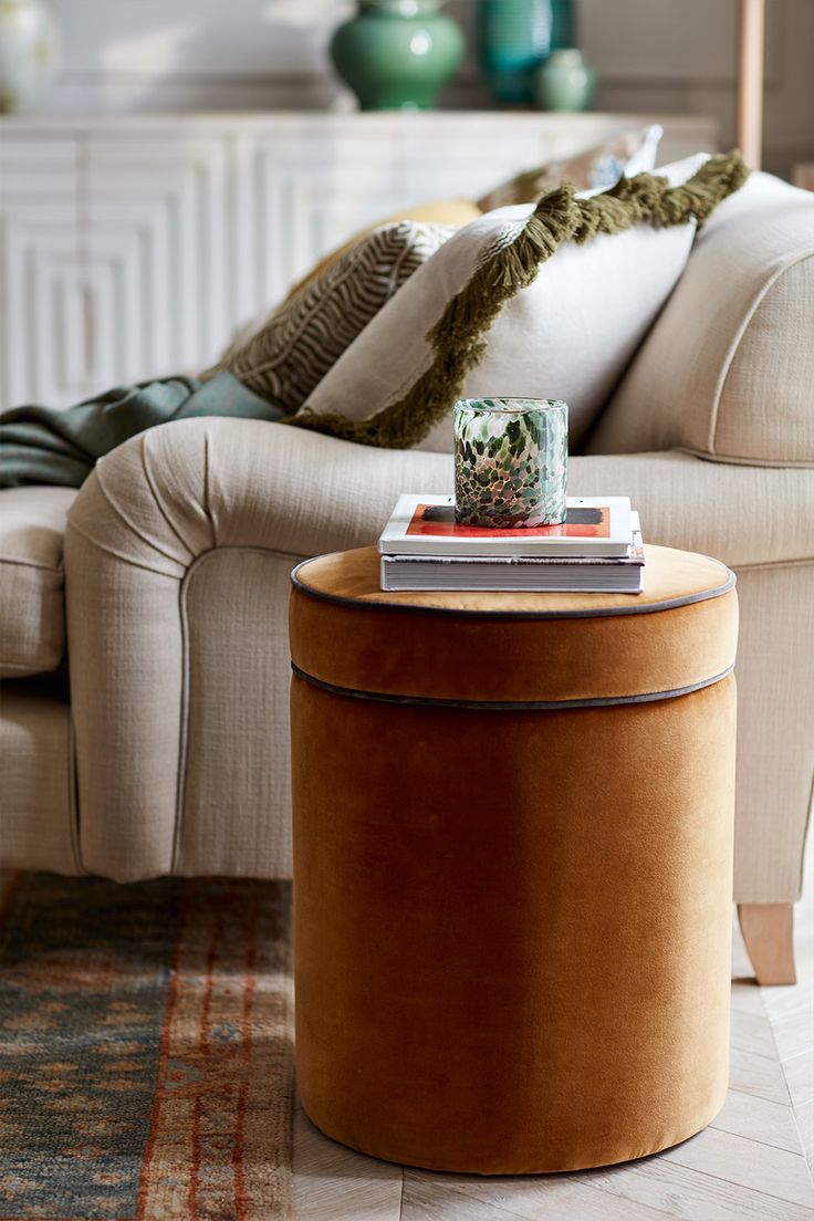 a living room with a couch, coffee table and books on the end table in front of it