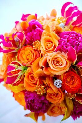 a bridal bouquet with orange, pink and purple flowers on it's side