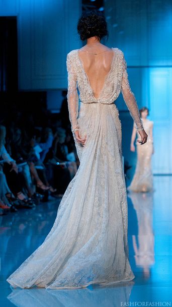 a woman walking down a runway wearing a dress with long sleeves and an open back