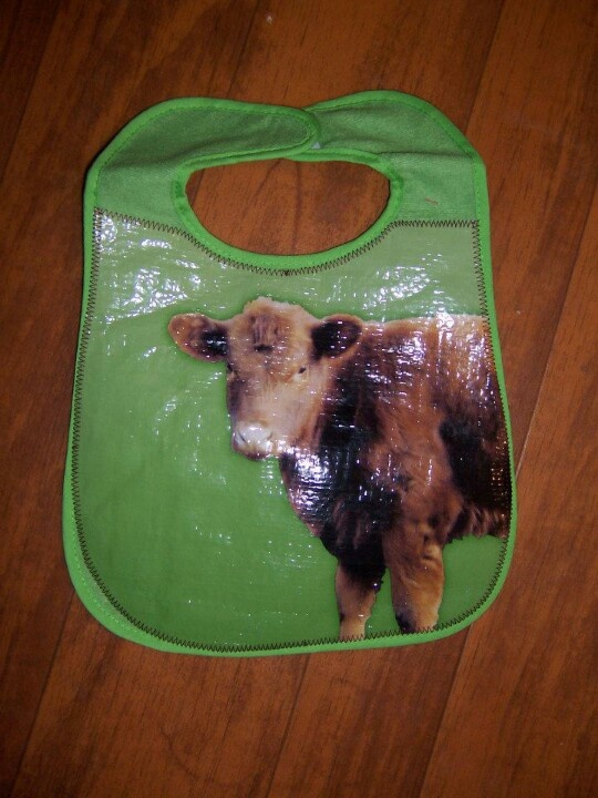 a brown and black cow laying on top of a green bib