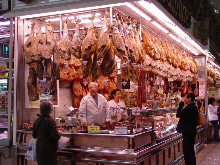 people are standing in front of a meat stand