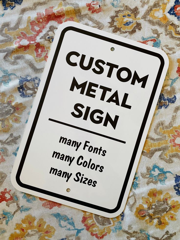 a white sign that says custom metal sign many font colors many sizes on the fabric