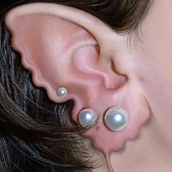 a close up of a person's ear with two pearls on the end of it