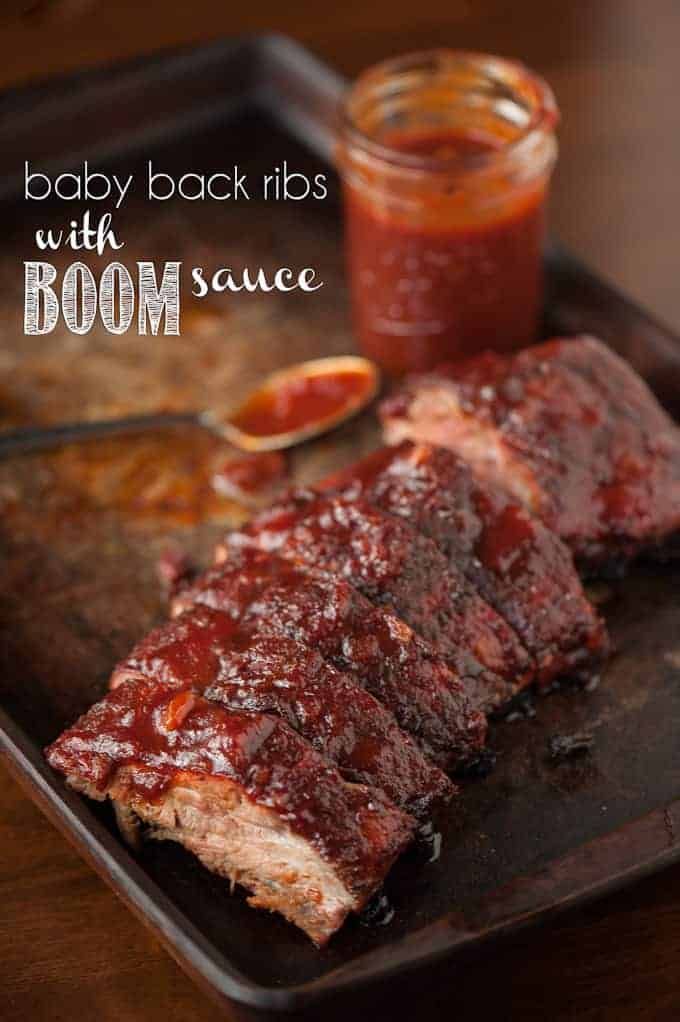 baby back ribs with bbq sauce on a black tray next to a jar of ketchup