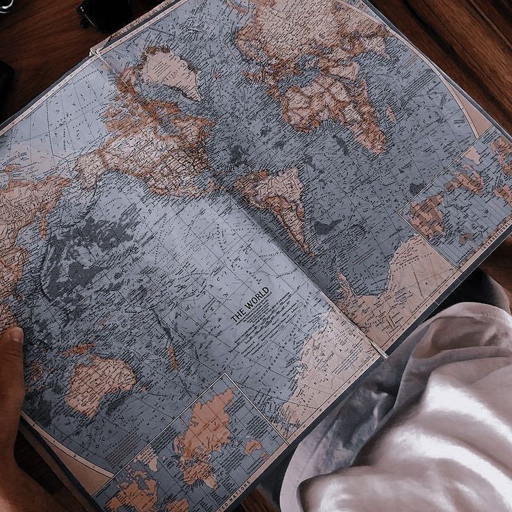 a person is looking at a map on a table with other items around them and holding it in their hands